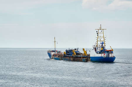 Trailing suction hopper dredger ship leaving cargo port terminal. Ventspils, Latvia, Baltic sea....