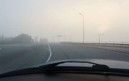 An empty asphalt road bridge (highway) in a thick fog. Pedestrian walkway, crossing, street lights. Dangerous driving, walking, cycling, traffic laws conceptsの写真素材