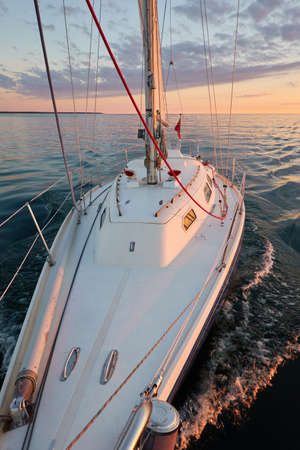 Yacht sailing in an open Baltic sea at sunset. Top down view of the deck and mast. Clear sky, golden...
