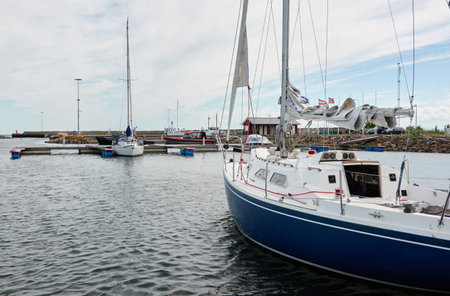 Sloop rigged sailboat (for rent and sale) moored to a pier in a yacht marina. Baltic sea. Nautical vessel, transportation, amateur sailing, summer vacations, cruising, recreation conceptsの写真素材