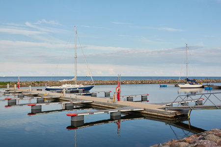 Sloop rigged sailboat (for rent and sale) moored to a pier in a yacht marina. Baltic sea. Nautical vessel, transportation, amateur sailing, summer vacations, cruising, recreation conceptsの写真素材