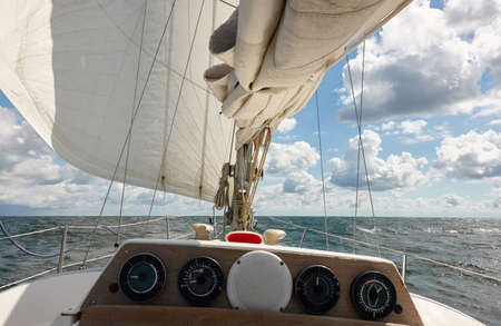 White yacht sailing on a sunny summer day. View of the mast and sails. Waves and water splashes. Clear blue sky. Baltic sea. Transportation, cruise, sport, recreationの写真素材