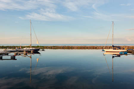 Sloop rigged sailboat (for rent and sale) moored to a pier in a yacht marina. Baltic sea. Nautical vessel, transportation, amateur sailing, summer vacations, cruising, recreation conceptsの写真素材