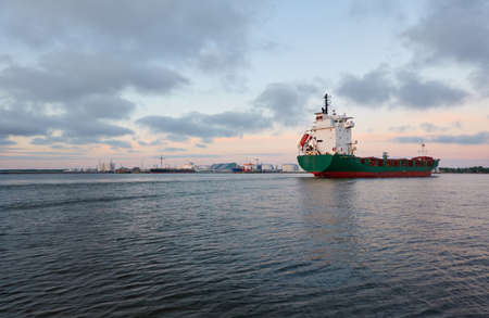 Large cargo ship sailing at sunset. Baltic sea. Panoramic view from a sailboat. Freight transportation, logistics, global communications, economy, business, industryの写真素材