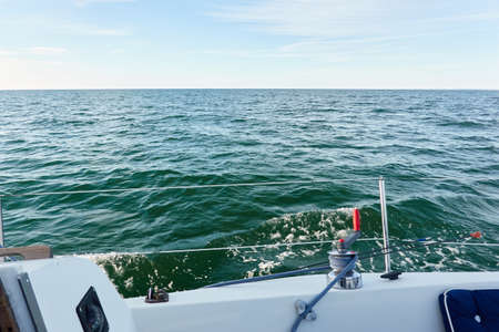 White yacht sailing at sunset. Boat side railing, winch, rigging equipment. View from the cockpit. Baltic sea. Transportation, leisure activity, cruise, sport, racing, yachting, summer vacationsの写真素材