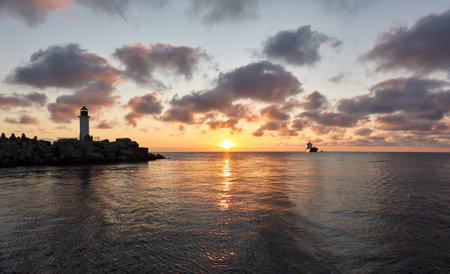 Baltic sea after the storm. Promenade to the lighthouse. Breakwaters. Dramatic sky, clouds, midnight sun. Nature, travel destinations. Panoramic view from a sailing boatの写真素材