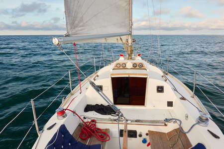 White yacht sailing on a sunny summer day. Top down (high angle) view of the deck, mast, sails....