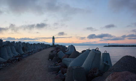 Baltic sea after the storm. Promenade to the lighthouse. Breakwaters. Dramatic sky, clouds, midnight sun. Picturesque dreamlike seascape, cloudscape. Nature, travel destinations. Panoramic viewの写真素材