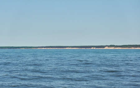 Baltic sea shore on a sunny day. View from a sandy beach sand dunes). Clear blue sky, turquoise water. Idyllic seascape, landscape. Pure nature, ecology, eco tourism, vacations. Spring, early summerの写真素材
