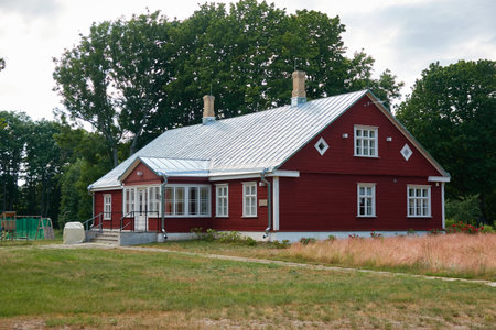 Modern red wooden country house with traditional architectural details. Building exterior. Summer garden, countryside. Scandinavia. Nature, vacations, eco tourism, rural area, villageのeditorial素材
