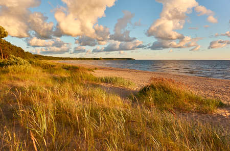 Baltic sea shore. Beach, sand dunes, dune grass. Dramatic sky, glowing sunset clouds. Picturesque panoramic scenery. Nature, environment, eco tourism, hiking, exploring conceptの写真素材