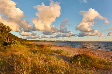 Baltic sea shore. Beach, sand dunes, dune grass. Dramatic sky, glowing sunset clouds. Picturesque panoramic scenery. Nature, environment, eco tourism, hiking, exploring conceptの写真素材