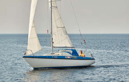 White sloop rigged yacht sailing in the Baltic sea on a clear day. Transportation, cruise, yachting, regatta, sport, recreation themes. Travel, exploring, wanderlust conceptsの写真素材