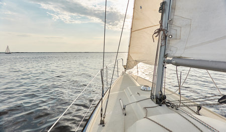 White sloop rigged yacht sailing in the Baltic sea after the storm. Waves, splashes, water surface. Cruise, summer vacations, regatta, sport, leisure activity, tourism, wanderlust conceptsの写真素材