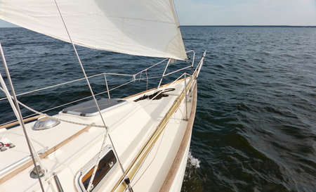 White sloop rigged yacht sailing in the Baltic sea after the storm. Waves, splashes, water surface. Cruise, summer vacations, regatta, sport, leisure activity, tourism, wanderlust conceptsの写真素材