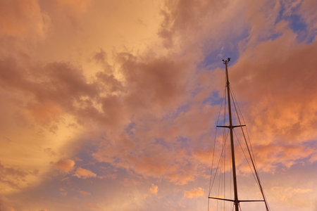 Yacht mast against colorful sunset sky with glowing cirrus and cumulus clouds after the storm.の写真素材