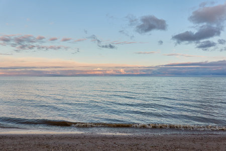Baltic sea shore (beach) at sunset, panoramic view. Soft sunlight, midnight sun, clear sky, glowing clouds. Saaremaa island, Estonia. Atmospheric summer landscapeの写真素材