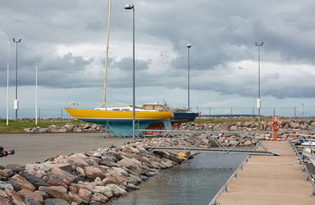 Yellow sailboat standing on land in a yacht marina. Kuivastu harbor, Estonia. Transportation, repair and service, cruise, recreation, amateur sailingの写真素材