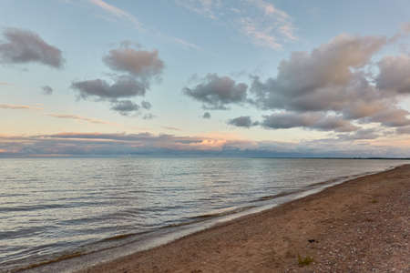 Baltic sea shore (beach) at sunset, panoramic view. Soft sunlight, midnight sun, clear sky, glowing clouds. Saaremaa island, Estonia. Atmospheric summer landscapeの写真素材