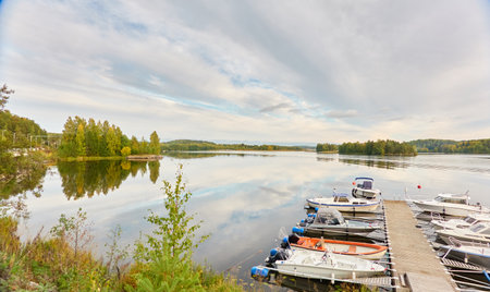 Motor boats, cutters and small fishing boats moored to a pier in a camping site. Forest in the background. Suiro lake (Kulovesi), Finland. Nature, vacations, recreation, ecotourism conceptsの写真素材