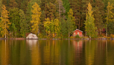 Small wooden house. Majestic evergreen forest and lake at sunset. Autumn. Suiro lake (Kulovesi), Finland. Panoramic view. Pure nature, ecotourism, remote places conceptsの写真素材