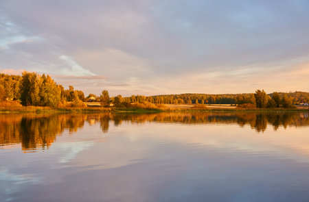 Majestic evergreen forest and lake at sunset. Soft golden sunlight, clear sky, glowing clouds.. Autumn. Suiro lake (Kulovesi), Finland. Panoramic view. Pure nature, ecotourism conceptsの写真素材