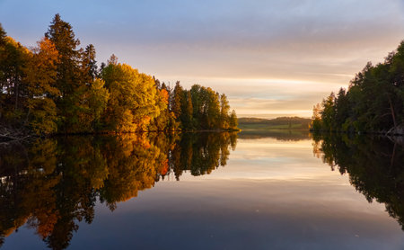 Majestic evergreen forest and lake at sunset. Soft golden sunlight, clear sky, glowing clouds.. Autumn. Suiro lake (Kulovesi), Finland. Panoramic view. Pure nature, ecotourism conceptsの写真素材