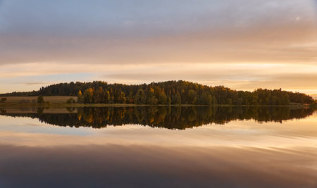 Majestic evergreen forest and lake at sunset. Soft golden sunlight, clear sky, glowing clouds.. Autumn. Suiro lake (Kulovesi), Finland. Panoramic view. Pure nature, ecotourism conceptsの写真素材