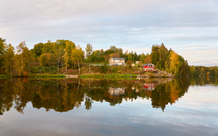 Small wooden house. Majestic evergreen forest and lake at sunset. Autumn. Suiro lake (Kulovesi), Finland. Panoramic view. Pure nature, ecotourism, remote places conceptsの写真素材