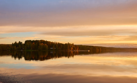 Majestic evergreen forest and lake at sunset. Soft golden sunlight, clear sky, glowing clouds.. Autumn. Suiro lake (Kulovesi), Finland. Panoramic view. Pure nature, ecotourism conceptsの写真素材