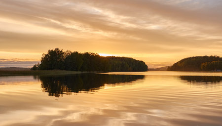 Majestic evergreen forest and lake at sunset. Soft golden sunlight, clear sky, glowing clouds.. Autumn. Suiro lake (Kulovesi), Finland. Panoramic view. Pure nature, ecotourism conceptsの写真素材