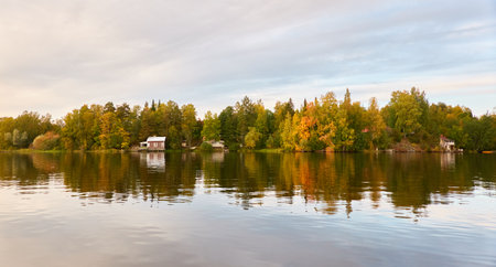 Small wooden house. Majestic evergreen forest and lake at sunset. Autumn. Suiro lake (Kulovesi), Finland. Panoramic view. Pure nature, ecotourism, remote places conceptsの写真素材