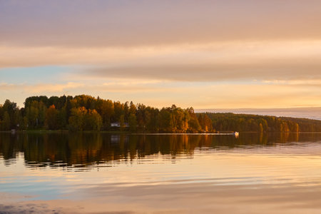 Majestic evergreen forest and lake at sunset. Soft golden sunlight, clear sky, glowing clouds.. Autumn. Suiro lake (Kulovesi), Finland. Panoramic view. Pure nature, ecotourism conceptsの写真素材