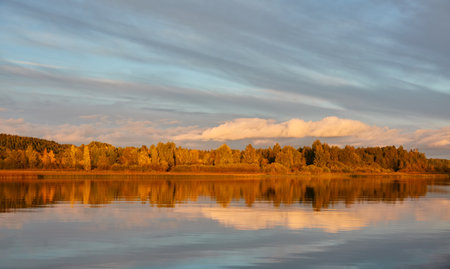 Majestic evergreen forest and lake at sunset. Soft golden sunlight, clear sky, glowing clouds.. Autumn. Suiro lake (Kulovesi), Finland. Panoramic view. Pure nature, ecotourism conceptsの写真素材