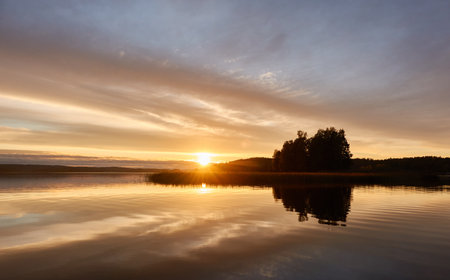 Majestic evergreen forest and lake at sunset. Soft golden sunlight, clear sky, glowing clouds.. Autumn. Suiro lake (Kulovesi), Finland. Panoramic view. Pure nature, ecotourism conceptsの写真素材