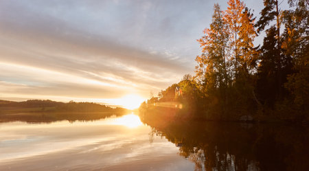 Majestic evergreen forest and lake at sunset. Soft golden sunlight, clear sky, glowing clouds.. Autumn. Suiro lake (Kulovesi), Finland. Panoramic view. Pure nature, ecotourism conceptsの写真素材