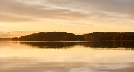 Majestic evergreen forest and lake at sunset. Soft golden sunlight, clear sky, glowing clouds.. Autumn. Suiro lake (Kulovesi), Finland. Panoramic view. Pure nature, ecotourism conceptsの写真素材