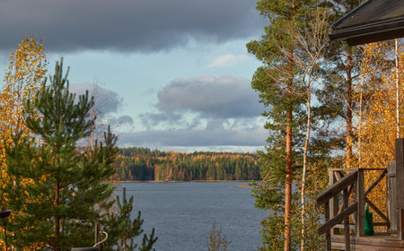Forest lake shore on a sunny day. Wooden house, terrace. Autumn landscape. Finland, Finnish nature. Ecology, fresh air, ecotourism, fishing, hunting, countryside life conceptsの写真素材
