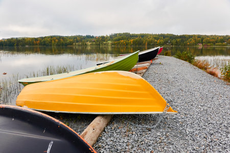 Small fishing rowing boats moored to a pier in a camping site. Colorful boats for rent. Forest in the background. Finland. Nature, vacations, recreation, ecotourism, lifestyle conceptsの写真素材
