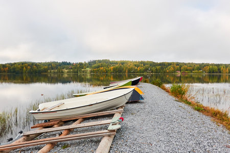 Motor boats, cutters and small fishing rowing boats moored to a pier in a camping site. Forest in the background. Finland. Nature, vacations, recreation, ecotourism, lifestyle conceptsの写真素材