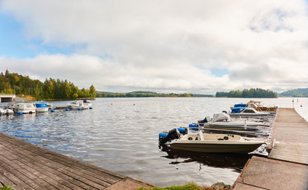 Motor boats, cutters and small fishing rowing boats moored to a pier in a camping site. Forest in the background. Finland. Nature, vacations, recreation, ecotourism, lifestyle conceptsの写真素材