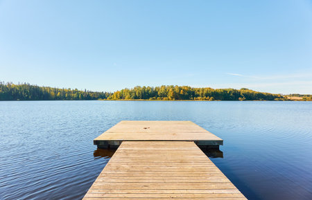 Forest lake on a sunny day. Wooden pier (boardwalk), resting zone, swimming area. Finland. Scandinavia, Europe. Autumn landscape. Nature, ecotourism, vacations and weekend getaway, safety conceptsの写真素材