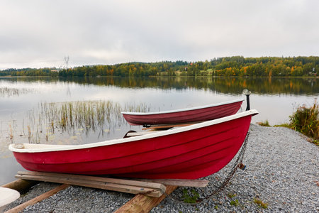 Small fishing rowing boats moored to a pier in a camping site. Colorful boats for rent. Forest in the background. Finland. Nature, vacations, recreation, ecotourism, lifestyle conceptsの写真素材