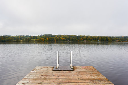 Forest lake (river) on a cloudy day..Wooden pier and swimming area. Glowing clouds after the rain. Finland. Idyllic autumn landscape. Pure nature, ecology, ecological reserve, ecotourismの写真素材