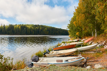 Motor boats, cutters and small fishing rowing boats moored to a pier in a camping site. Forest in the background. Finland. Nature, vacations, recreation, ecotourism, lifestyle conceptsの写真素材