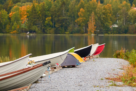 Small fishing rowing boats moored to a pier in a camping site. Colorful boats for rent. Forest in the background. Finland. Nature, vacations, recreation, ecotourism, lifestyle conceptsの写真素材