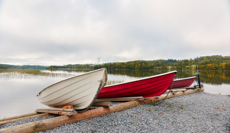 Small fishing rowing boats moored to a pier in a camping site. Colorful boats for rent. Forest in the background. Finland. Nature, vacations, recreation, ecotourism, lifestyle conceptsの写真素材