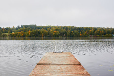 Forest lake (river) on a cloudy day..Wooden pier and swimming area. Glowing clouds after the rain. Finland. Idyllic autumn landscape. Pure nature, ecology, ecological reserve, ecotourismの写真素材