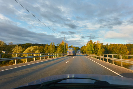 Asphalt road (highway) through the forest. Concept autumn landscape. Transportation, trucking, logistics, freedom, travel, tourism, wanderlust, the way forward themesの写真素材