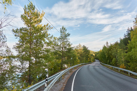 Asphalt road (highway) near the forest lake. Sunny day. Concept autumn landscape. Transportation, logistics, freedom, travel, tourism, wanderlust, the way forward themesの写真素材